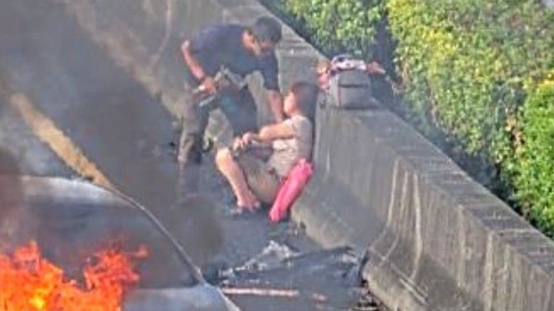 後方轎車駕駛、副駕駛順利脫困後，2人飽受驚嚇蹲坐在路邊。（圖／翻攝畫面）