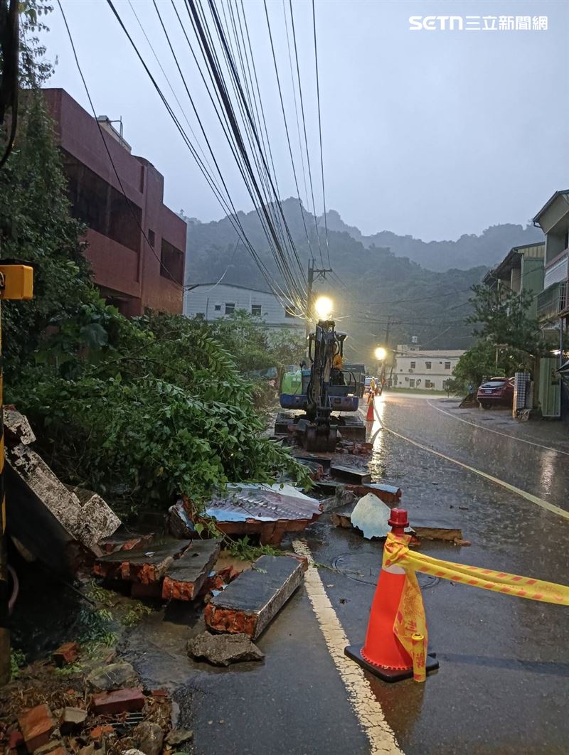 一處紅磚圍牆在短時間強降雨後突然倒塌，伴隨巨大聲響，磚瓦與碎石瞬間散落一地，佔據整個車道。（圖／翻攝畫面）
