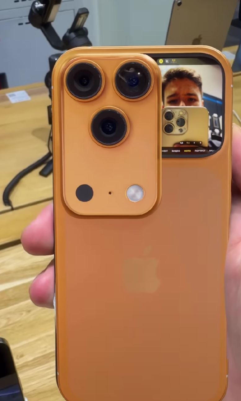 圖為 IG 流傳的影片截圖,橘色 iPhone 17 Pro Max 螢幕左下滑出小鏡頭,讓自拍者即時看到自己,但也有網友質疑這是 AI 偽造影像。(圖/翻攝自IG)