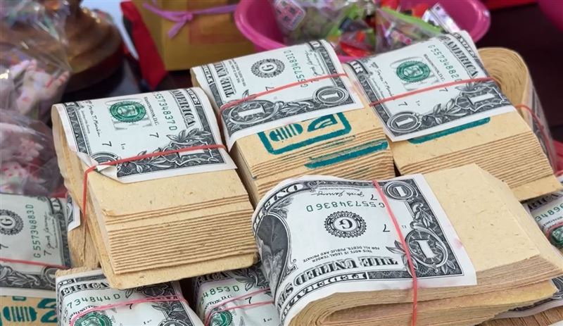 民眾開搶道長發放的「施食」，其中綁著1元美鈔的紙錢最搶手。(圖／翻攝畫面)