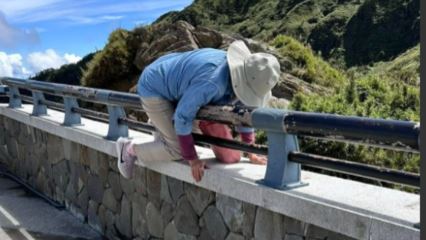 大媽到合歡山出遊，竟翻過路邊護欄，站上沒有安全維護的岩石上拍照。（圖／翻攝自爆料公社）