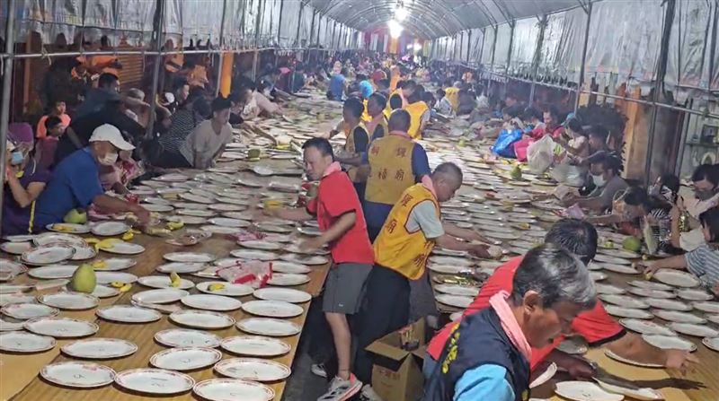 擔心爭搶發生意外，工作人員協助將桌上供品推給民眾方便拿取。(圖／翻攝畫面)