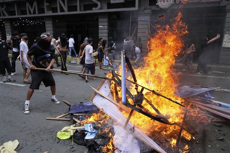 菲律賓21日反貪腐示威爆發警民衝突，抗議群眾火燒雜物，意圖阻擋鎮暴警察。（圖／美聯社／達志影像）