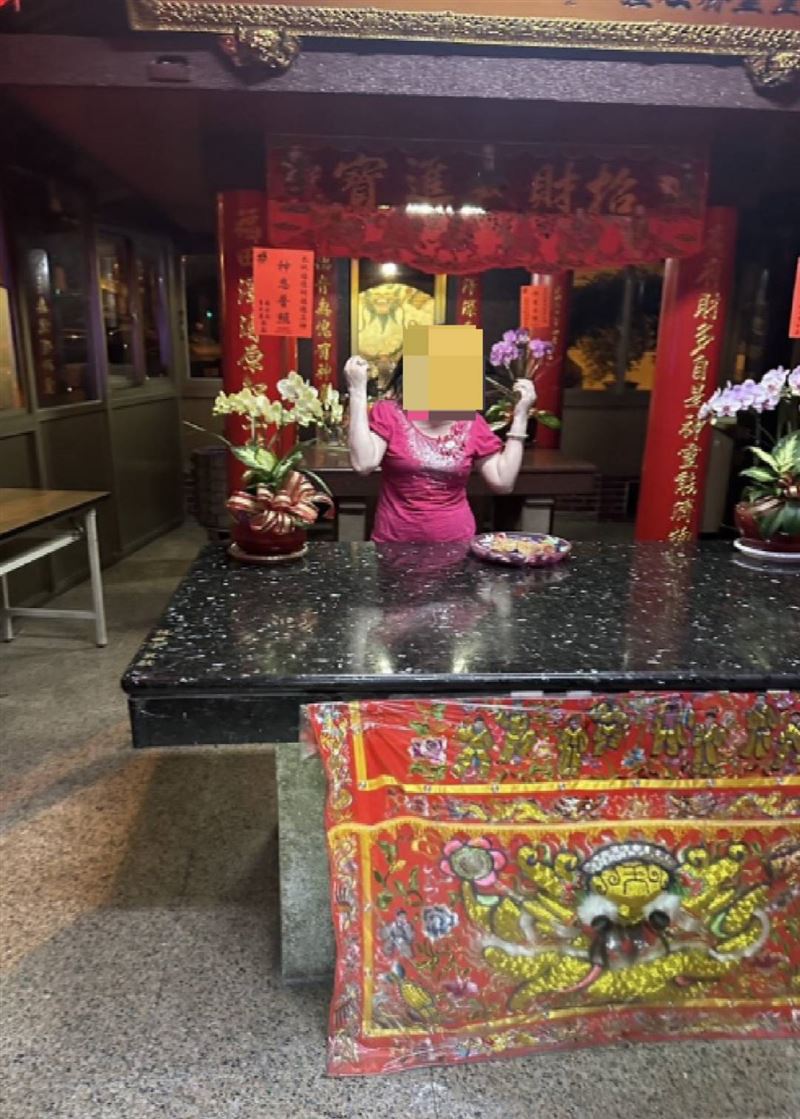 穿著全套紅衣褲的老奶奶蹲坐在土地公廟神桌下方。（圖／翻攝畫面）