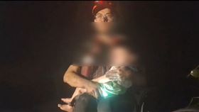 屏東消防局徒步執行光復災區搜救，過程中，搭乘橡皮艇的搜救人員手中緊抱男童並喊話「弟弟不要怕，馬上就帶你出去」。（屏東消防局提供）