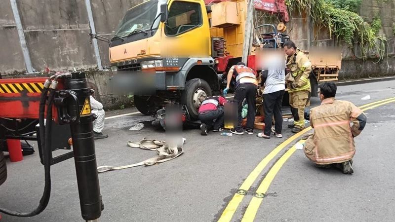 騎士下坡過彎不慎失控打滑，當場卡進吊車車底。（圖／翻攝畫面）