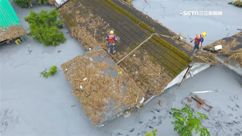 搜救隊攀爬在防資上，切開一個個鐵皮屋頂，找尋失聯民眾