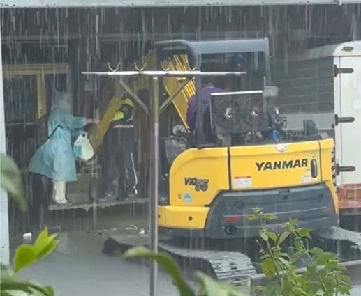 員警坐上怪手的抓斗前往民宅，協助受困婦女撤離。（圖／翻攝畫面）