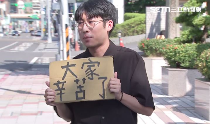 陳姓鏟子超人被李明璇指控霸佔車票、唱島嶼天光=青鳥的奇妙指控，因此現身國民黨中央黨部外，要李明璇出來道歉。記者會結束時也舉著「辛苦了」的紙牌和在場媒體致謝。（圖／翻攝畫面）
