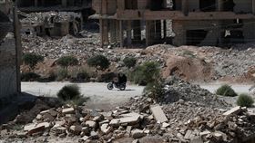 直到阿塞德獨裁政權倒台為止，敘利亞歷經了14年的內戰。圖為一對情侶騎摩托車經過首都大馬士革郊區的戰後廢墟。（圖／美聯社／達志影像）