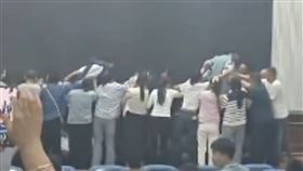 名家長跪成一排，蒙眼的學生在攙扶下依序踏過家長背部。（圖／翻攝自極目新聞）