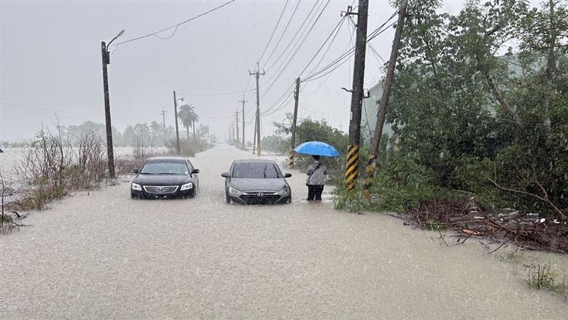 嘉義鄉道嘉22線遭豪雨灌爆，兩部車輛拋錨路中央，一名民眾撐傘苦等救援，畫面如災難電影重現。（示意圖／讀者提供）