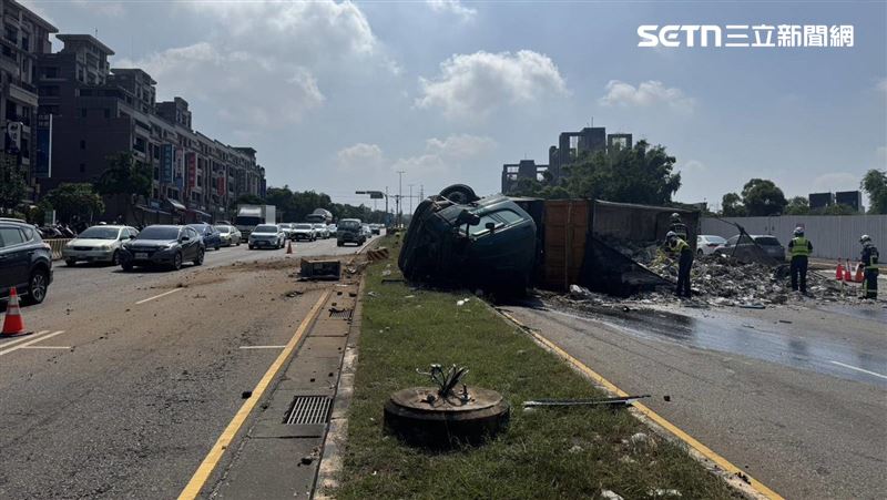 一輛大型砂石車疑似在下坡路段失控，衝至對向車道後翻覆，車體側倒占據多線車道，導致往市區方向交通一度中斷。（圖／翻攝畫面）