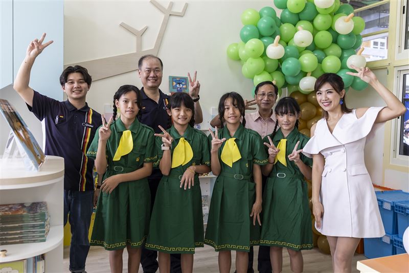 在充滿童趣的芙朝國小第55所歐德幸福圖書室，左起陳彥霖設計師、陳國甫總經理、校長周金木與孩子開心合影