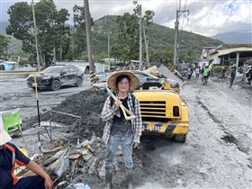 呂小姐背著鏟子站在災區道路旁 笑著說我們不能氣餒