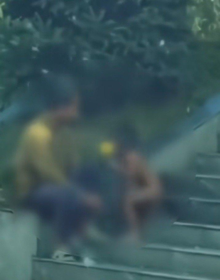 那孩子嘴叼球狀物體，交給疑似為家長的大人。（圖／翻攝自微博）