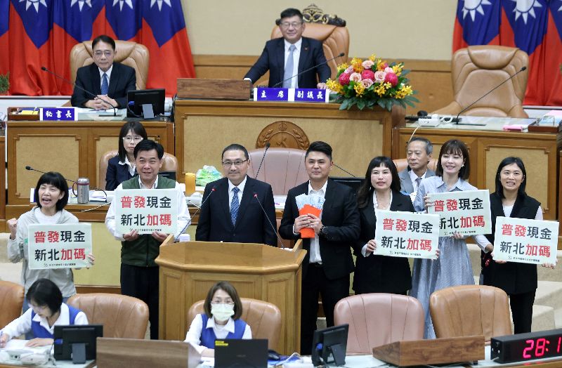 新北市議會28日進行市政總質詢,民進黨團要求市府在中央普發現金新台幣1萬元時,加碼市民每人4.6萬元;市長侯友宜(立者左3)表示,市府債都還沒還完,要如何發現金,這說不過去