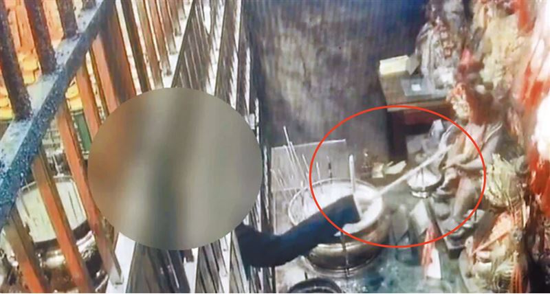 男子拿著長棍，試圖將掛在神像上的金牌勾出來。（圖／翻攝畫面）