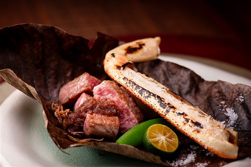 「和牛松葉蟹朴葉燒」選用北海道 A5 和牛搭配松葉蟹腳，以獨特的朴葉燻烤手法，讓蟹肉鮮香與和牛油脂在高溫下交織出迷人層次。(圖／blu koi壽司割烹料理提供）