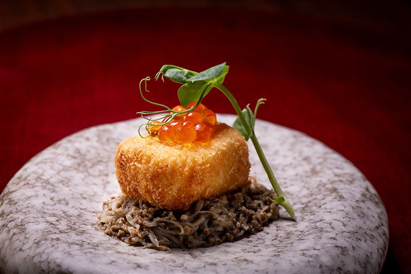 師傅將蟹味增、蟹肉填入蟹殼炙烤後，再搭配可樂餅食用。(圖／blu koi壽司割烹料理提供）