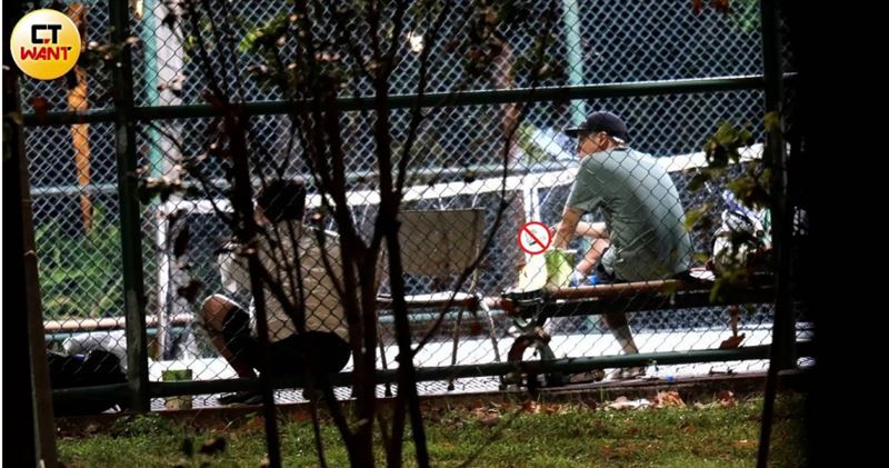 周湯豪1與男性友人在台北內湖某公園網球場邊聊天邊抽菸。（圖／CTWANT）