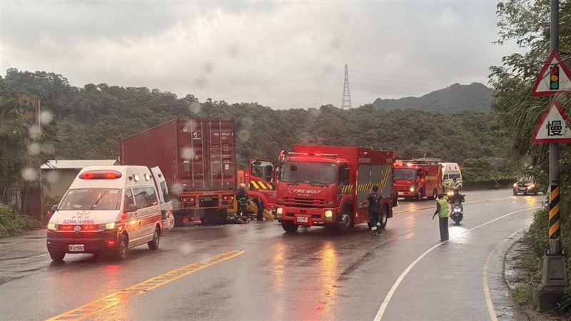 事故發生後現場散落破碎車殼與物品，機車倒臥路中，騎士倒在貨櫃車後方輪軸處，動彈不得。（圖／翻攝畫面）