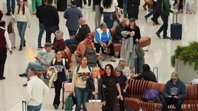 因航班延誤，許多民眾只能持續坐著等待。（圖／美聯社／達志影像）