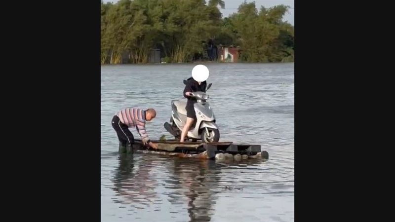 宜蘭五結鄉利澤村淹大水，一名護理師出門上班用竹筏幫忙拖載機車。（圖／翻攝畫面）