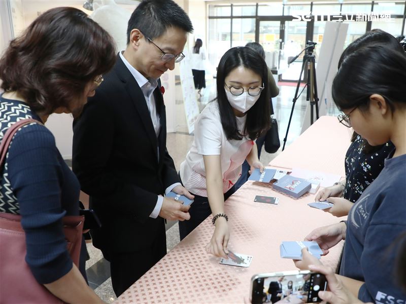 衛福部疾管署長羅一鈞（左2）和學生一起玩HIV生存戰卡牌。（圖／中山醫大提供）