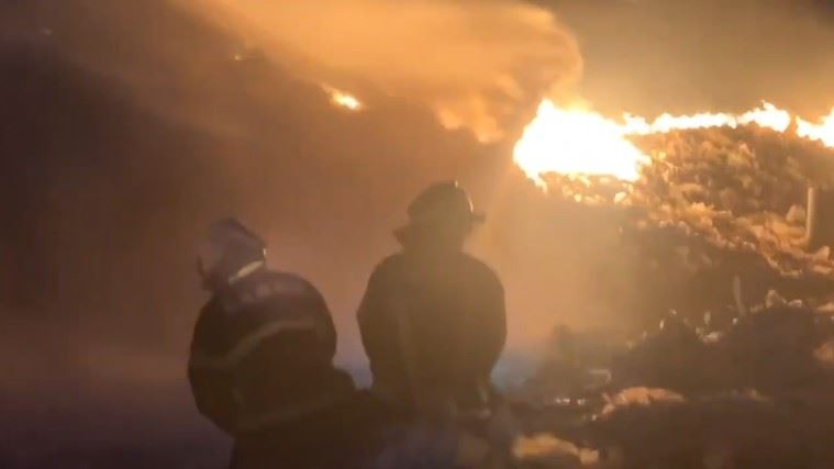 消防隊人員在場內山坡佈設水線，徒步往高處推進，試圖射水滅掉垃圾堆內部火勢，但場內廢棄物目前都還在持續燃燒。（圖／翻攝畫面）