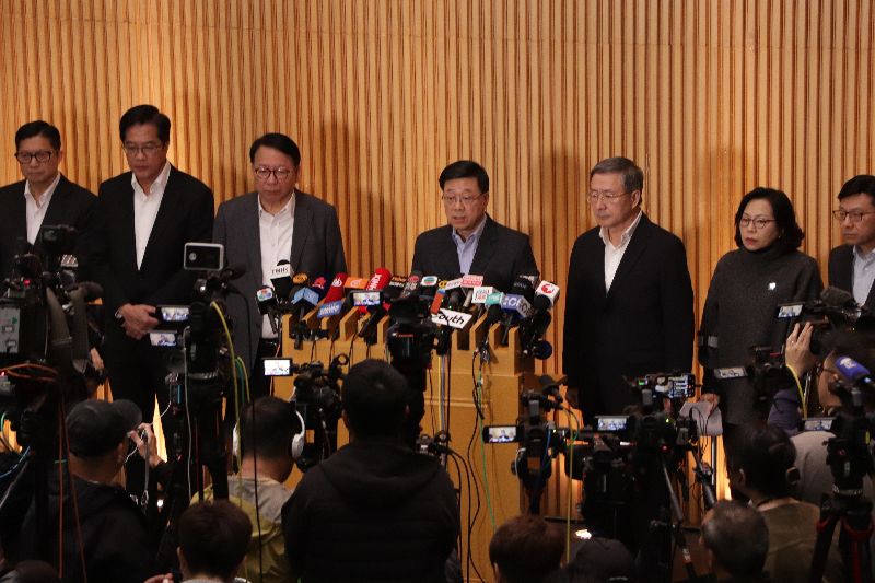 香港政府因為宏福苑大火挨轟，特首李家超（後排中間）粉專也被洗版。（圖／中央社）