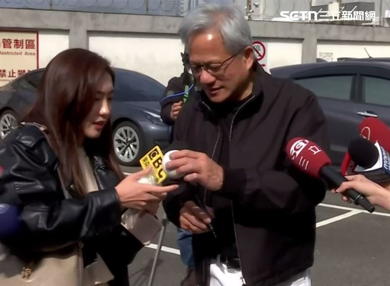 輝達執行長黃仁勳在機場邊受訪邊簽名，並回答了羅唯仁赴英特爾任職一事。（圖／三立新聞）