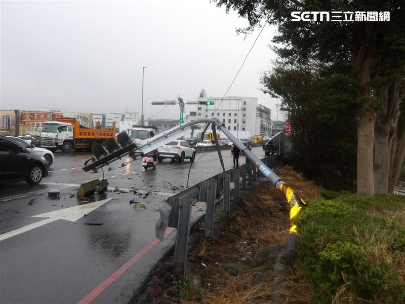 白色轎車路口撞斷號誌桿，害電纜線垂落，路過大貨車貨物纏繞電纜線又扯斷另一支號誌桿。（圖／翻攝畫面）