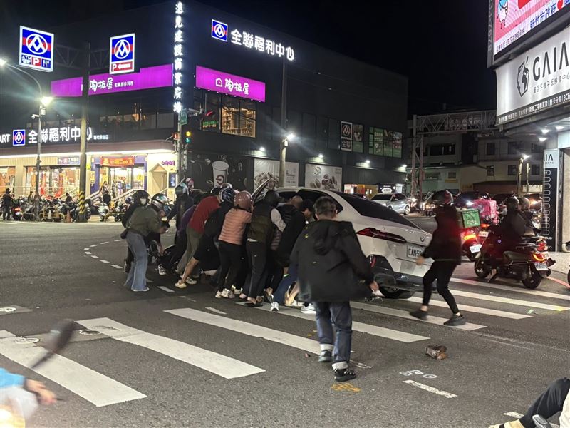 大家合力將BMW抬起，救出女騎士。(圖／翻攝自新竹市議員黃文政臉書)