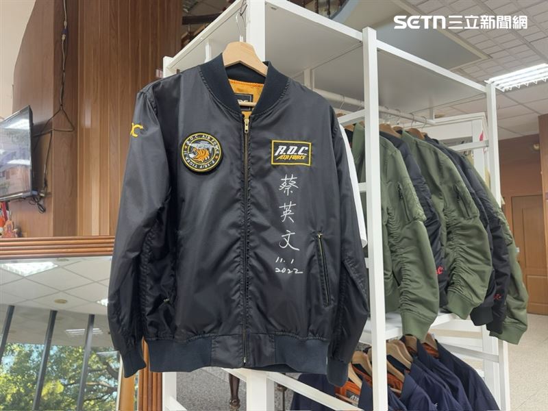 漢翔不只造戰機,更變身最硬派軍工潮牌!翔園總座吳經文揭密,當年IDF砍單危機竟逼出熱銷25年、具醫療級研發背景的「抗壓神枕」;還有腳掌繡著「國機國造」的超萌勇鷹熊家族 與精緻臂章。靠著「七分行銷」策略,曾創下一小時狂掃8萬元紀錄,成功將軍工魂變現金。圖為前總統蔡英文簽名的帥氣飛行夾克。(圖/記者師瑞德攝影)