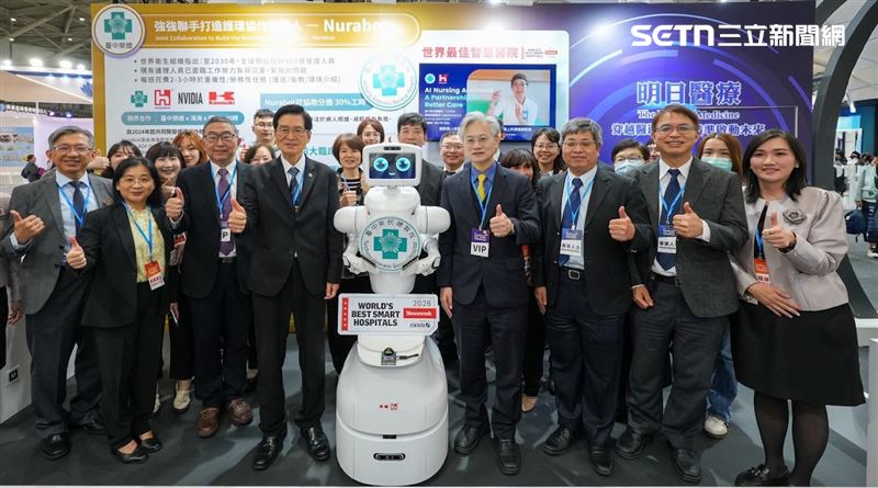 退輔會主委嚴德發(前排左4)和臺中榮總院長傅雲慶(前排右4)及團隊成員和護理協作機器人Nurabot合影。(圖/翻攝畫面)
