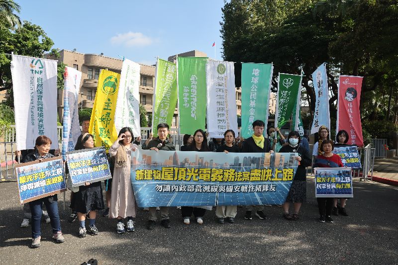 民間團體今(10）日在行政院前舉行記者會呼籲行政院儘速在年底前公告「建物光電設備標準」，並堅定維持草案原有的適用範圍。（圖／中央社）