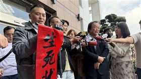 新黨副秘書長游智彬拿著印有「生死狀」的紅布條在王世堅受訪時鬧場（圖／記者劉秀敏攝影）