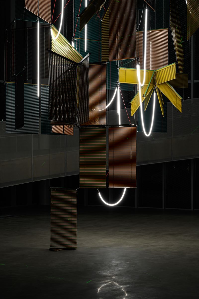梁慧圭 ( Haegue Yang )，《流動奉獻－樹蔭三合》（夜間），2025，鋁製百葉窗、粉末塗層鋁懸掛結構、鋼纜、LED燈管、雷射照明、開關電源、無線模組、電線，2,362 x 1,086 x 1,086公分，藝術家自藏，臺中市立美術館委託創作。（圖／臺中市立美術館提供）