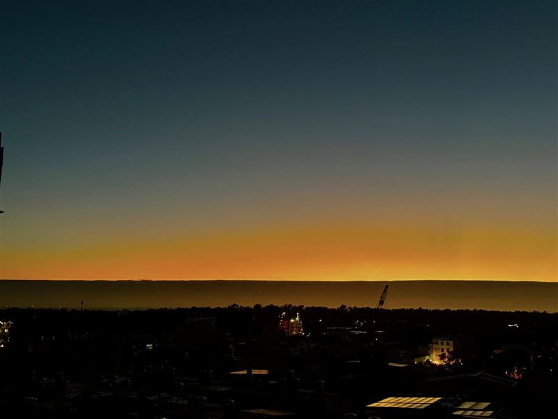 譚艾珍分享,10日在台南從陽台看往漁光島,發現夕陽的光輝下,還有一層長長的黑色屏障。(圖/翻攝自譚艾珍臉書)