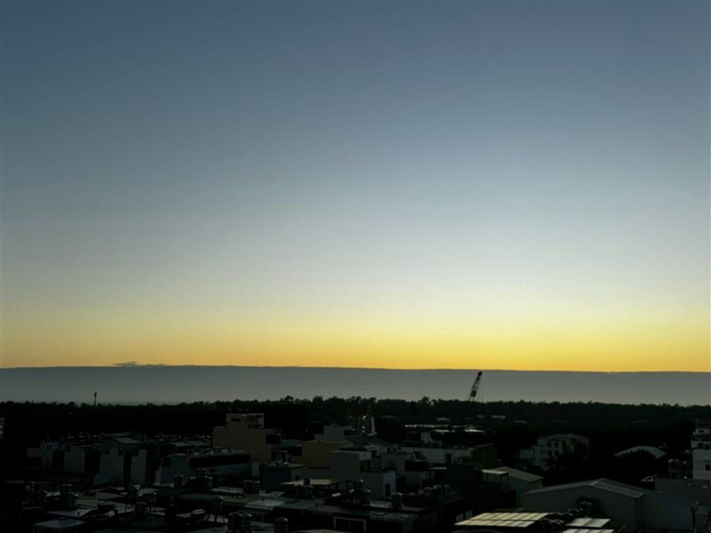 陸地的建築與夕陽光輝隔著一片黑色雲層,相當壯觀。(圖/翻攝自譚艾珍臉書)