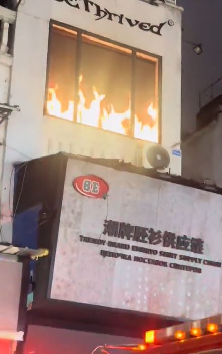 中國廣州一處街道，眾人看到對面商家「起火」趕緊叫消防隊，殊不知那只是看板。（圖／翻攝自微博）