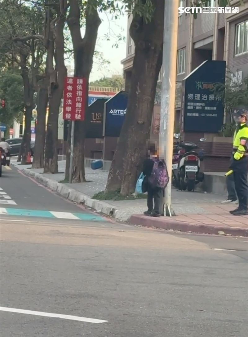 看起來像低年級的小朋友在等紅綠燈,一旁的員警也注意到他。(圖/網友___.gladys授權提供)