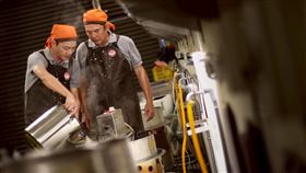 洪都拉斯跟藍葦華在工廠場景中專注製豆腐。（圖／民視提供）