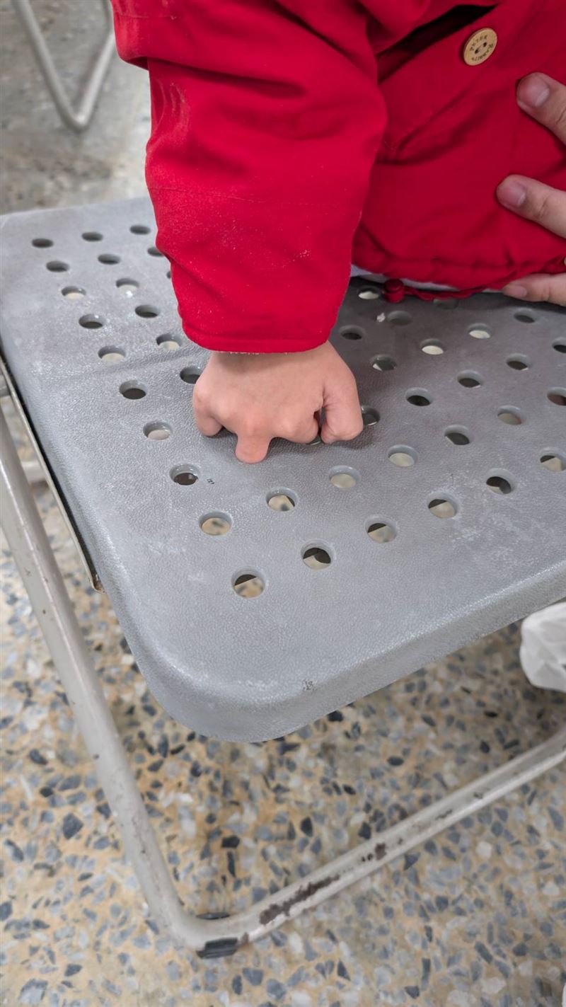 女童手指卡住因緊張疼痛大哭，救護人員連人帶椅送往急診室處置。(圖／翻攝畫面)