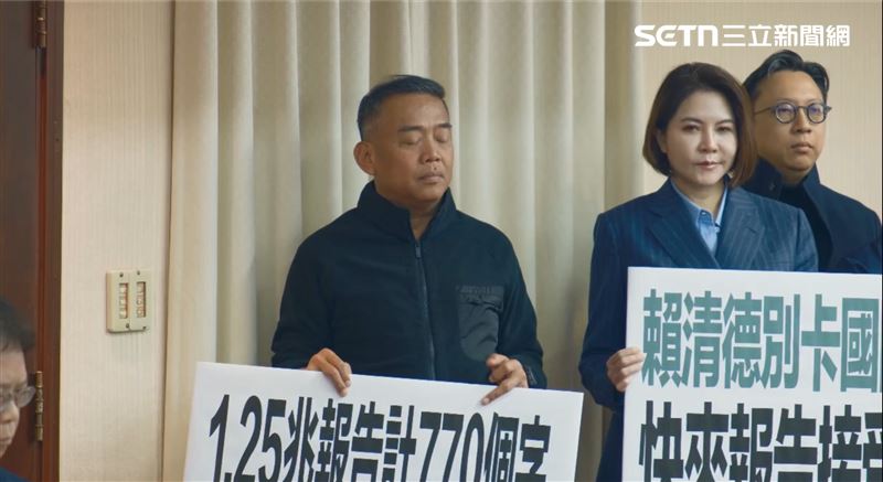 盧縣一在羅智強發言時，站在一旁舉著牌子，雙眼卻闔上「閉目養神」。（圖／記者楊士誼攝影）