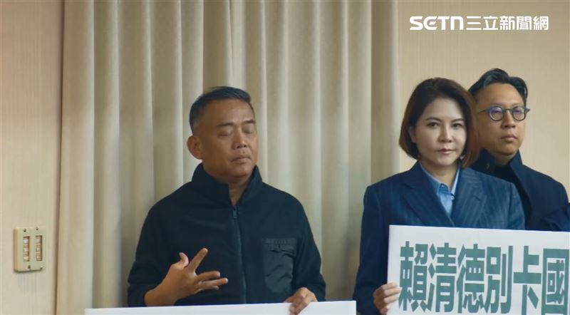 盧縣一在羅智強發言時，站在一旁舉著牌子，雙眼卻闔上「閉目養神」，更活動活動舉著牌子的雙手。（圖／記者楊士誼攝影）