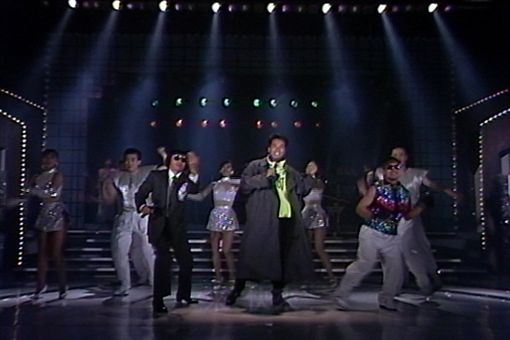 曹西平身穿螢光色運動上衣搭配長版及膝外套,被豬哥亮笑稱「是穿雨衣來表演嗎?」(圖/資料畫面)