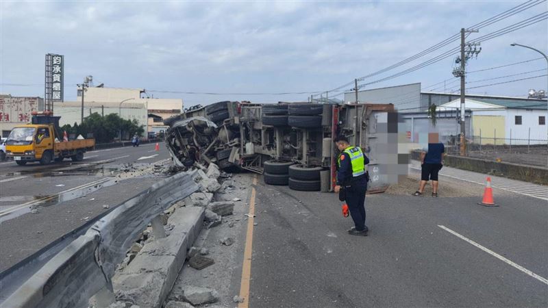 砂石車因爆胎翻覆後一路輾過護欄，車上的油水砂石掉滿整個路面。（圖／翻攝畫面）