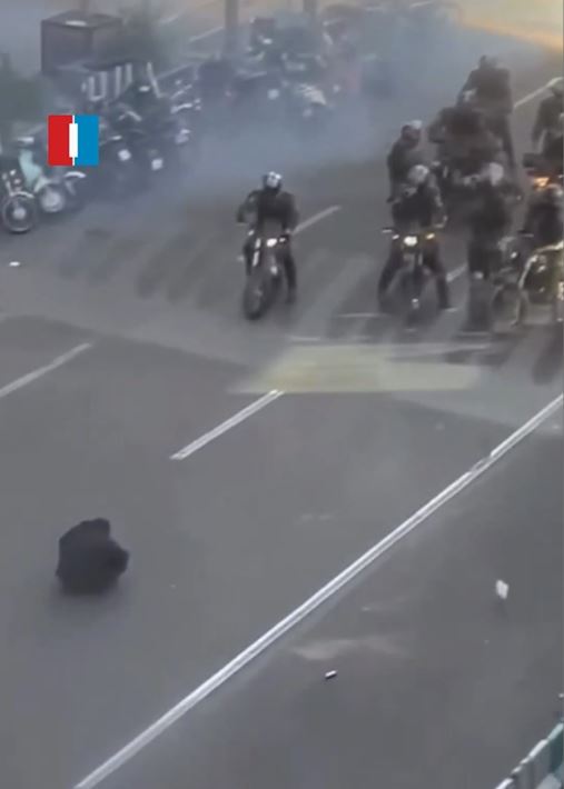 一名男子用外套遮住頭，擋住催淚彈的攻擊，手無寸鐵、沉默蹲坐在德黑蘭的街道上，以「肉身」阻擋軍警部隊前進。（圖／翻攝自X＠IranIntl_En）